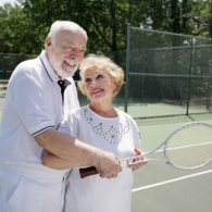 Senior man gives his wife pointers on tennis.