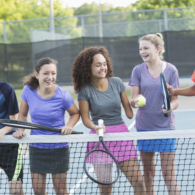 Multi-ethnic teenagers playing tennis.  Girl in middle (17 years, mixed race) is a physically challenged amputee.